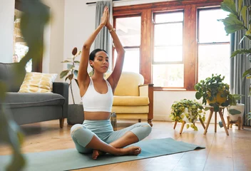 Fotobehang Yoga, woman and hands above head for meditation, training and exercise at home living room, wellness and holistic health. Calm biracial person meditate, prayer or praying position in pilates workout © Nina/peopleimages.com