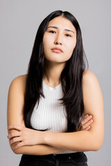 Asian girl in bad mood standing on grey background in studio isolated.