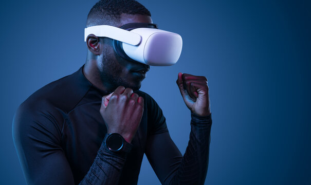 Fit young black guy practicing boxing in VR glasses