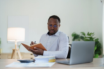 middle aged man American African using computer laptop with planning working on financial document, tax, exchange, accounting and Financial advisor