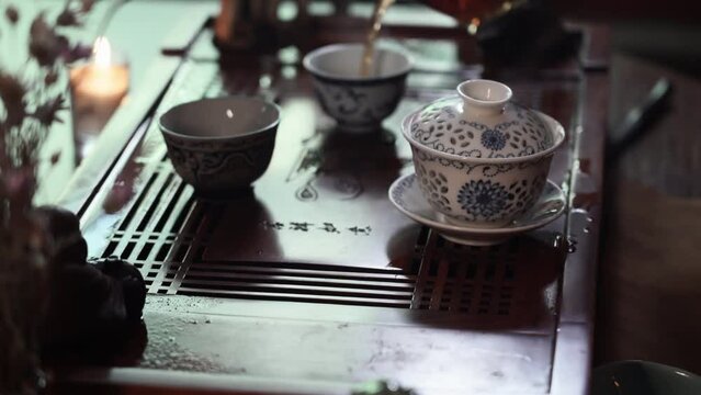 female tea master in kimano pours hot pu-erh into bowls during the tea ceremony, close-up