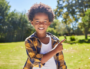 African boy, pointing and park portrait with smile, happiness or playful in outdoor sunshine. Young...