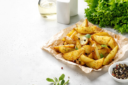 Roasted potatoes with herbs, spices and greens. Baked potato wedges on craft paper. Dinner idea. Copy space for text.
