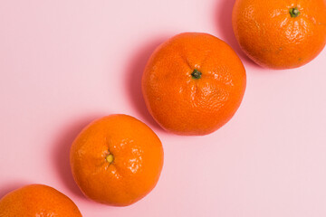 Tangerines on pink paper background with copy space.