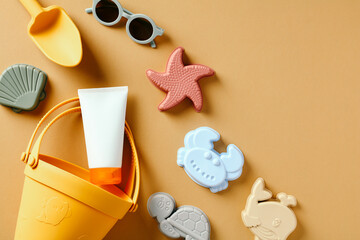 Kids sand molds, summer accessories and sunscreen cream bottle on sandy background.