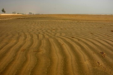 Fototapeta premium Sand texture design on sea beach for background. Wave pattern of ocean sand on the beach.
