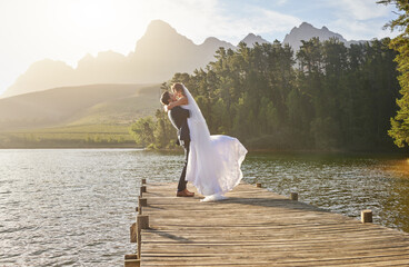 Kiss, dance and a married couple on a pier over a lake in nature with a forest in the background...