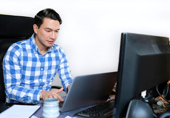 A man in a checked shirt working from home at a desk