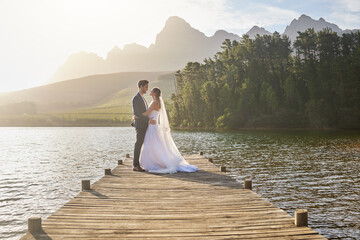 Married, bride and groom on a pier over a lake in nature with a forest in the background after...