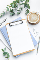 Modern white office desk table with coffee, notebook and other supplies.