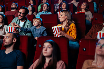 Cute child with parents at movies.