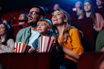 Joyful family watching movie in cinema. - obrazy, fototapety, plakaty