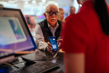 Senior man paying with mobile app in theater.