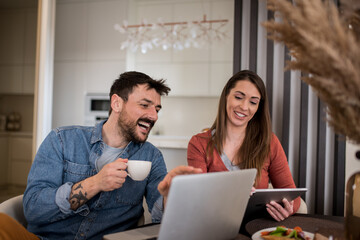 Couple drinking coffee while working during breakfast at home.