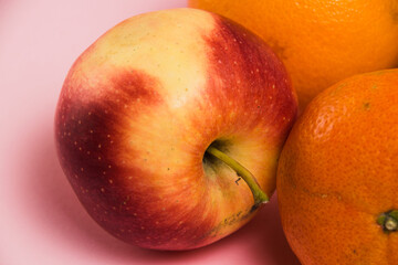 Fruits pomegranate, lemon, apple, oranges and tangerine on a pink background close-up. Delicious fruits on a bright background.