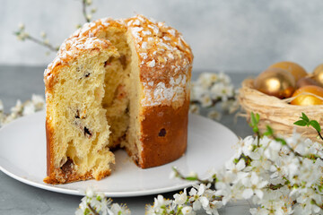 Cut Easter cake on plate decorated with spring flower branches
