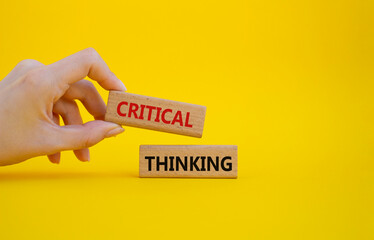 Critical thinking symbol. Wooden blocks with words Critical thinking. Businessman hand. Beautiful yellow background. Business and Critical thinking concept. Copy space.