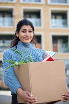 Portrait Of Female University Or College Student Outdoors Moving Into Campus Room Carrying Box