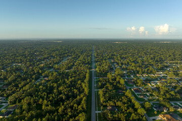 Aerial view of american small town in Florida with private homes between green palm trees and suburban streets in quiet residential area