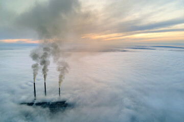 Aerial view of coal power plant high pipes with black smoke moving up polluting atmosphere at sunset