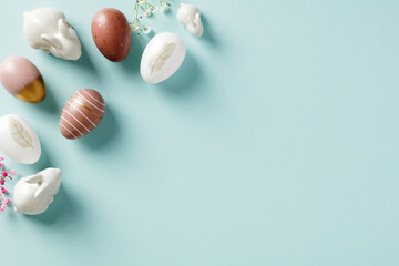 Easter eggs, decorative bunnies, flowers on pastel blue background. Easter concept. Flat lay, top view