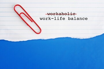 Torn paper on blue copy space background with text WORKAHOLIC, crossed off to WORK LIFE BALANCE, to balance work and life commitments, to avoid burnout, anxiety or negative effects of too much stress