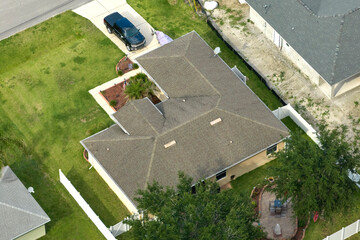 Aerial view of typical contemporary american private house with roof top covered with asphalt shingles and green lawn on yard