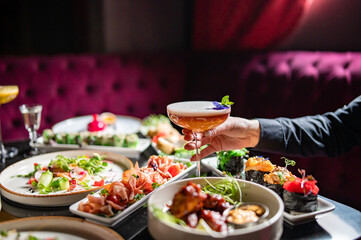 woman hand holding glass with cocktail in restaurant