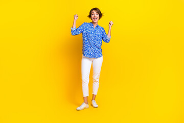 Full length photo of positive lucky lady wear print shirt shouting rising arms isolated yellow color background