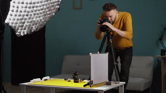 Male photographer shooting beauty products on the table in his home studio.