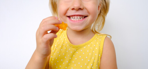 cheerful small child holds candy, blonde girl 3 years old wants eat gelatinous sweets with smile,...