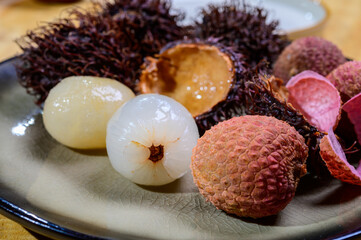 Tasty tropical exotic fruits, ripe fresh peeled and unpeeled lychee and hairy rambutan southeast Asian fruits  rambutan southeast Asian fruits