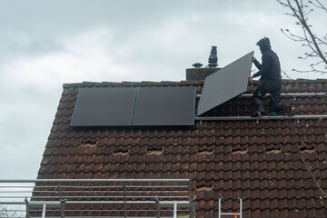 Installing of solar panels on roof in cloudy winter day, green energy in Europe