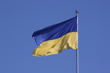 waved flag of Ukraine on flagpole