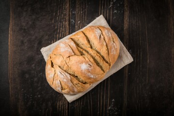 delicious freshly baked bread resting on top of a tea towel on a brown wooden table
