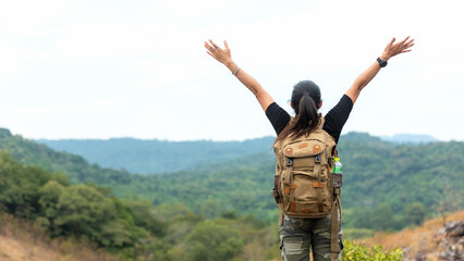 Hiker asian woman backpack raise hands happy feeling freedom good and strong weight victorious facing on the natural mountain. Traveler going camping outdoors destination leisure