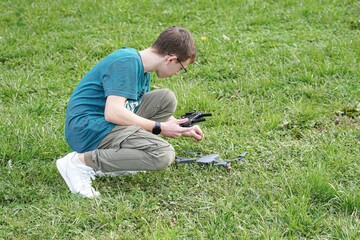 Naklejka na ściany i meble A boy in a field launches a quadcopter and controls it from the remote control.