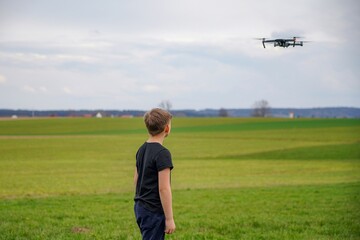 A boy in a field launches a quadcopter and controls it from the remote control.