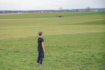 The boy controls the flight of the quadcopter using the remote control.