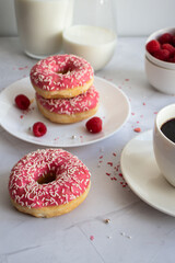 Donuts with coffee and milk. 
Donut with pink frosting 