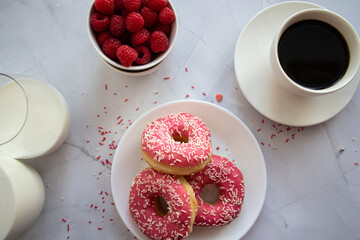 Donuts with coffee and milk. 
Donut with pink frosting 