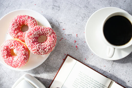 Donuts with coffee and milk. 
Donut with pink frosting 