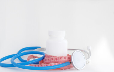white pills bottle with vitamin c capsules with stethoscope and measure tape.loss weight slim fit concept healthy nutrition food supplements
