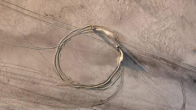Two Motocross creating circle donut on the beach near the ocean