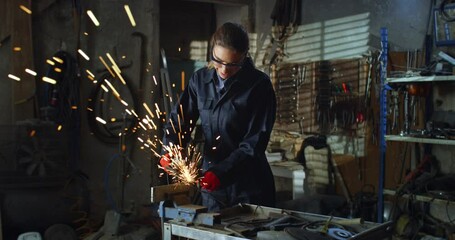 Portrait of Professional Female Welder Using Angle Grinder to Polish Metal with Sparks Flying Off in Repair Workshop. Young Female Mechanic in Uniform Overalls and Protective Goggles Doing Maintenance - Powered by Adobe