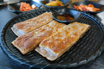 This crepe-like korean dish is made by pan-frying buckwheat batter and  rolling it with chopped radish, napa cabbage, and meat as a filling.