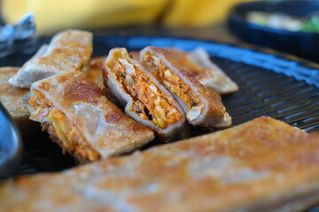 This crepe-like korean dish is made by pan-frying buckwheat batter and  rolling it with chopped radish, napa cabbage, and meat as a filling.