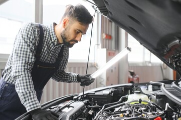 Professional Mechanic is Working on a Car in a Car Service. Repairman in Safety Glasses is Fixing...