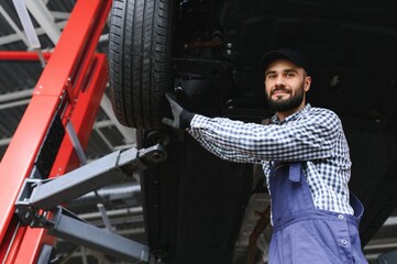Fototapeta na wymiar Portrait of a mechanic repairing a lifted car
