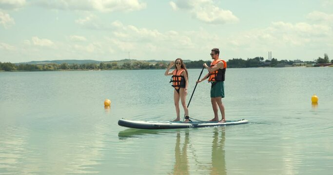 Beautiful couple on paddleboards surfing on the lake